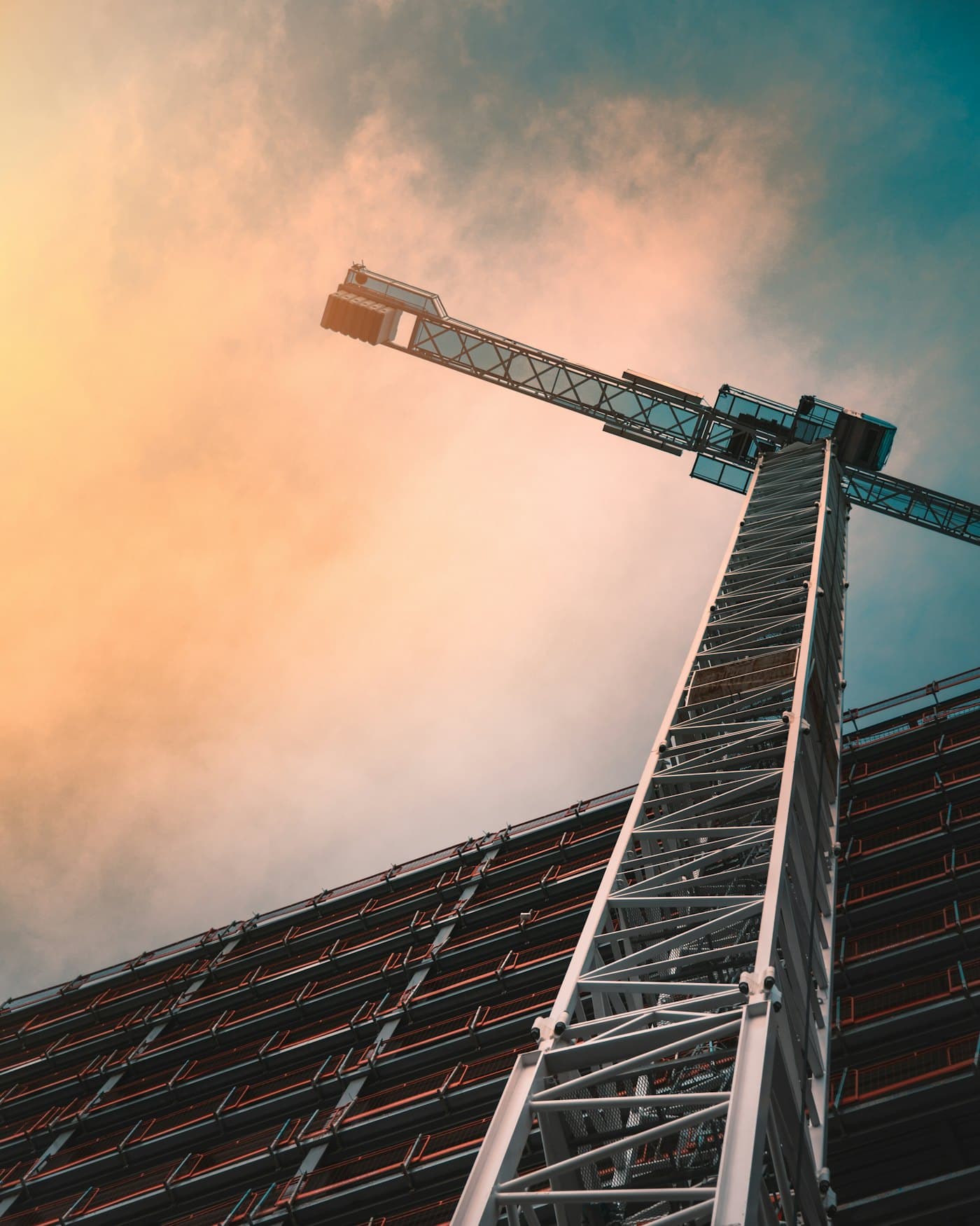 Tower crane rising over a building frame at sunset