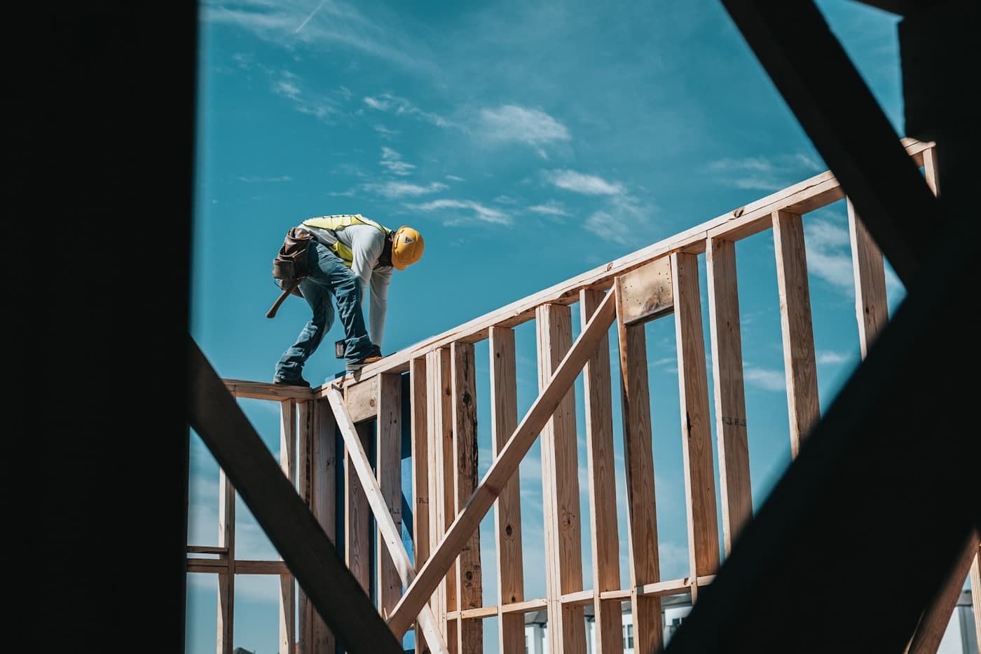 Carpenter working on timber framing against an open sky