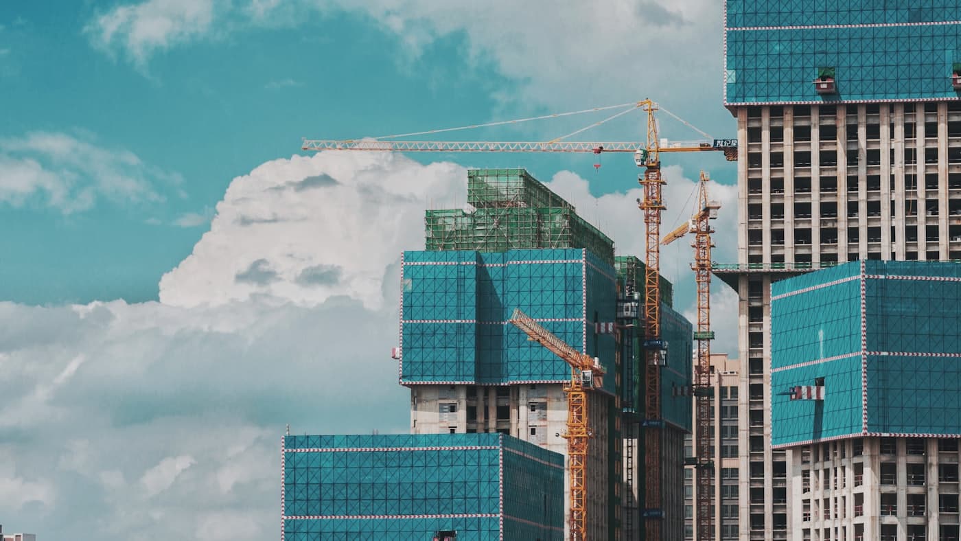 High-rise towers under construction wrapped in green safety netting